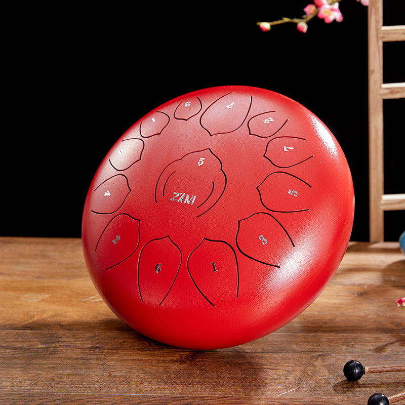 A red steel tongue drum with ZANI branding, displayed on a wooden surface.