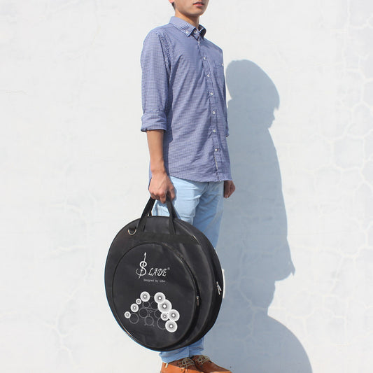 A person holding a black portable drum kit cymbal bag with white text and logo on it