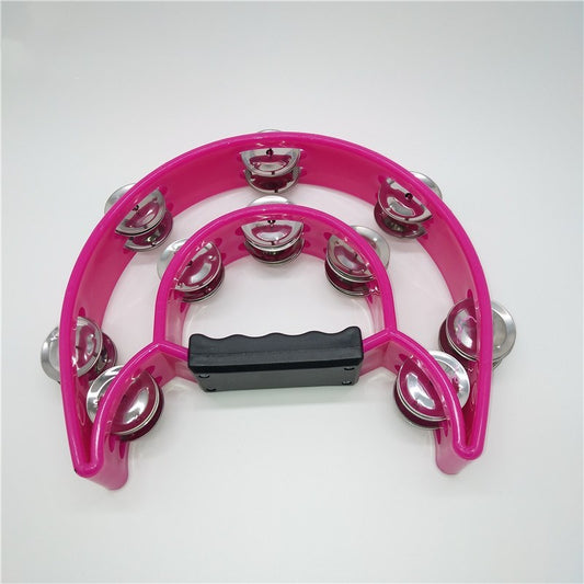 A pink hand crank musical instrument resembling a tambourine with metal jingles.
