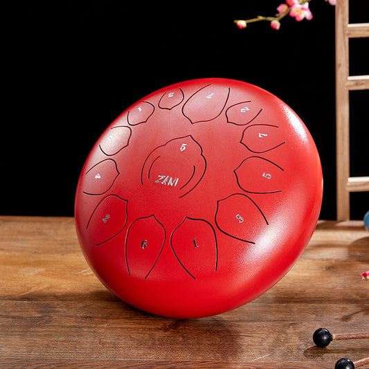 A red steel tongue drum with ZANI branding, displayed on a wooden surface.