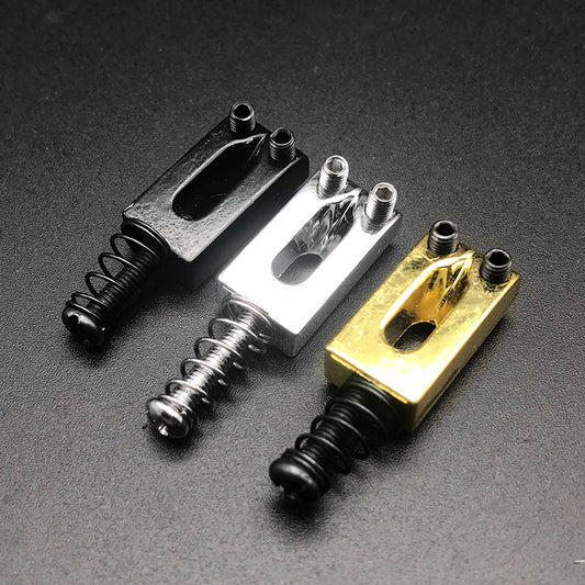 Three color options of guitar tailpieces arranged in a row, with the middle one selected, showcasing black, silver, and gold color options. Each tailpiece has a spring attached to it.