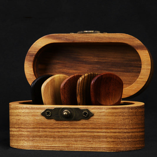 A set of wooden guitar picks displayed inside an open wooden box with a dark background.