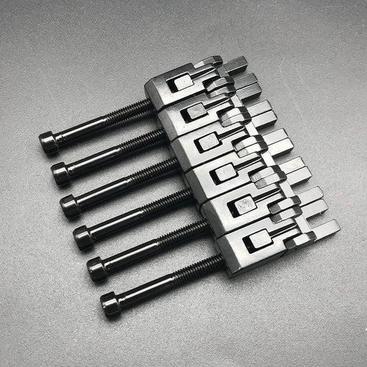 A set of metal guitar string rollers, arranged in parallel, with varying lengths, against a dark background.