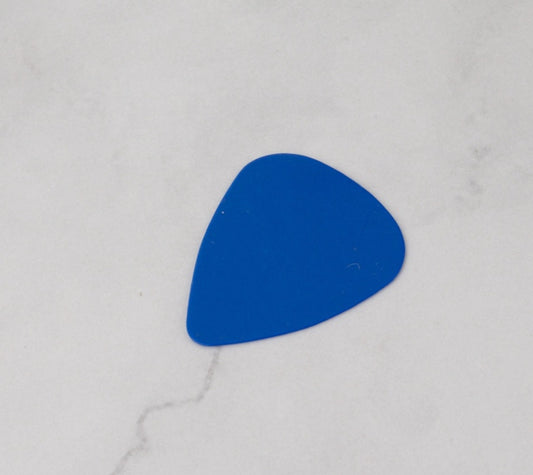 A single blue ABS smooth guitar pick placed on a marble surface.
