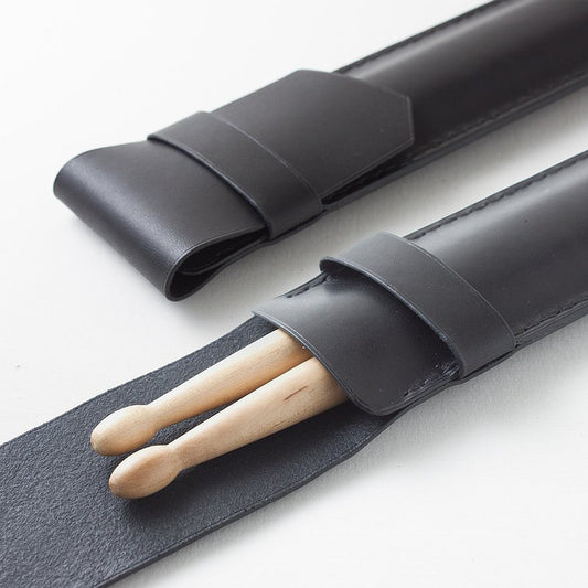 A leather drum stick bag with a pair of drumsticks partially inserted into the bag, showcasing the fit and style of the accessory.